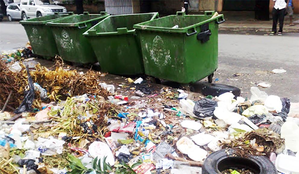 Newspaper photograph of empty waste containers with garbage on the ground  around them.