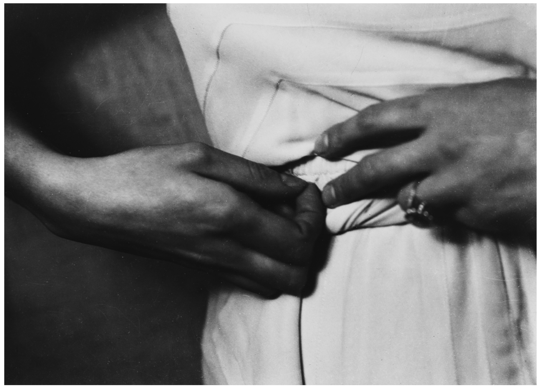 A person's hands pin clothing at the waist